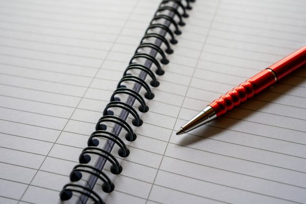 a red pen sitting on top of a notebook
